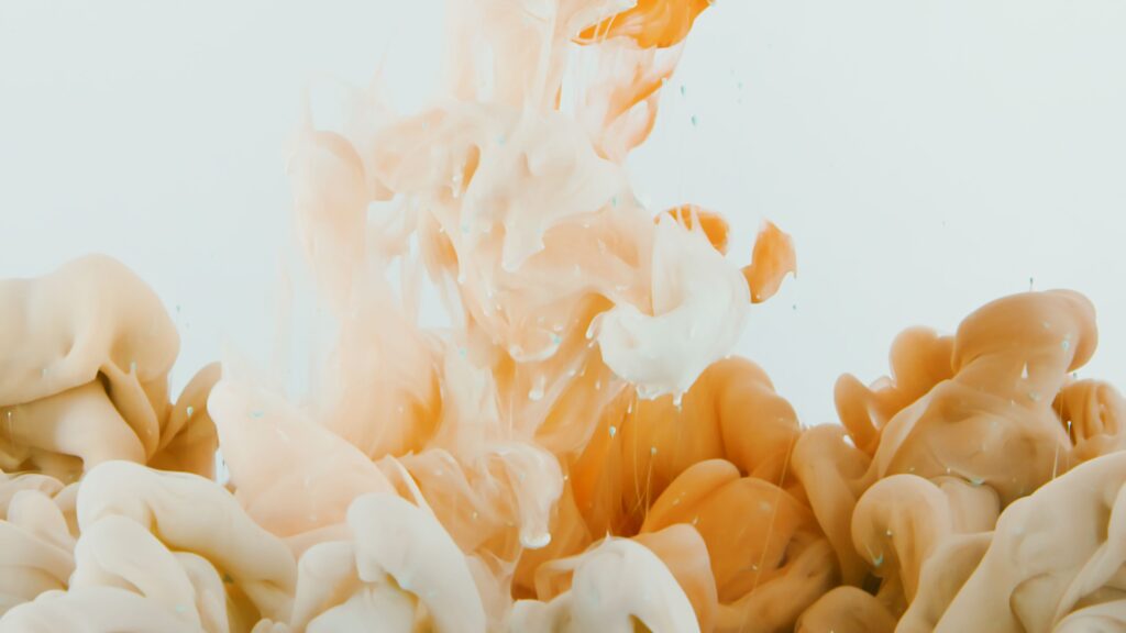 Dynamic splashes of orange and white paint creating abstract, fluid patterns.